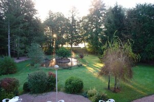Um jardim com lago, rodeado por árvores e arbustos.