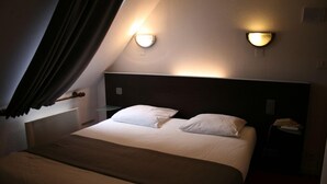 A hotel room with a bed, two bedside lamps, a nightstand, and a window with curtains. - Hotel Le Tronçais (Saint-Bonnet-Troncais)