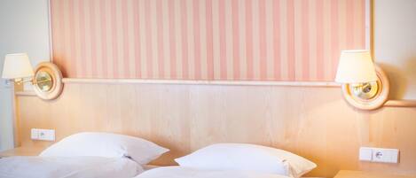Een hotelkamer met twee bedden, een houten hoofdeinde en bedlampen.