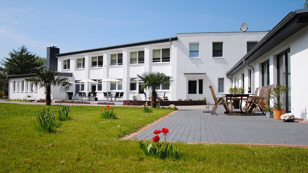Een modern gebouw met een patio, buitenmeubels en potplanten.
