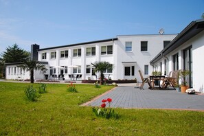 A modern building with a patio area, outdoor seating, and potted plants. - Appartementanlage-Ferienwohnungen Weiße Möwe (Sassnitz)
