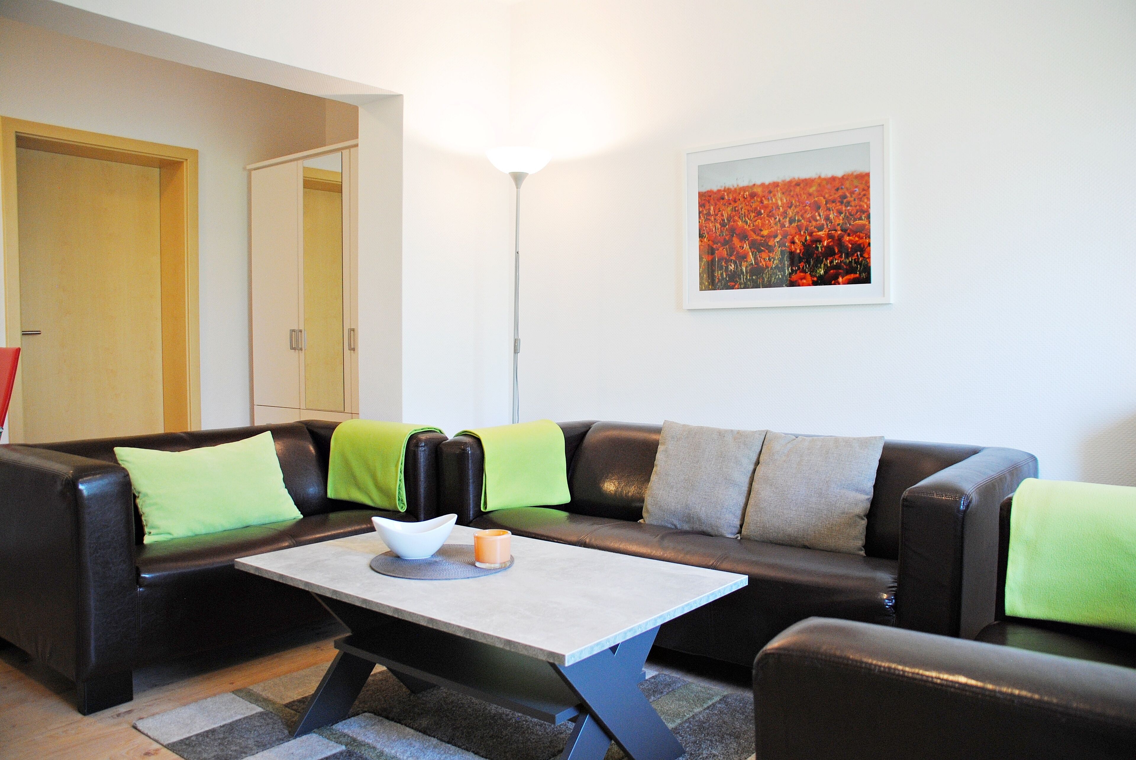 A living room with a sofa, a coffee table, and a painting on the wall.