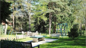 Een park met een picknicktafel, banken en speeltoestellen.