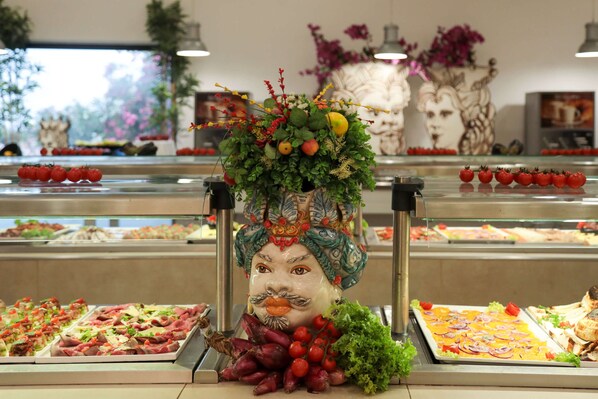 A buffet with various food items and a decorative centerpiece. - I Giardini di Athena – Athena Resort (Ragusa)
