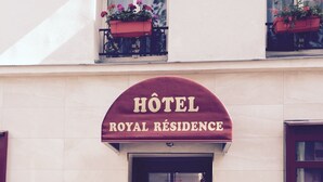 L’entrée d’un hôtel, avec une enseigne indiquant : « HÔTEL ROYAL RESIDENCE ».