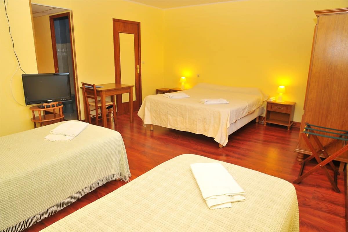 A hotel room with two beds, a TV, a desk, and a wardrobe.