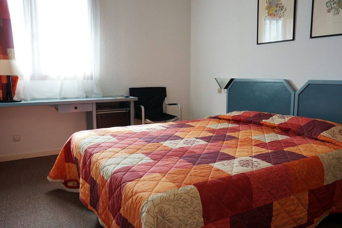 A bedroom with a bed, a desk, and a chair.
