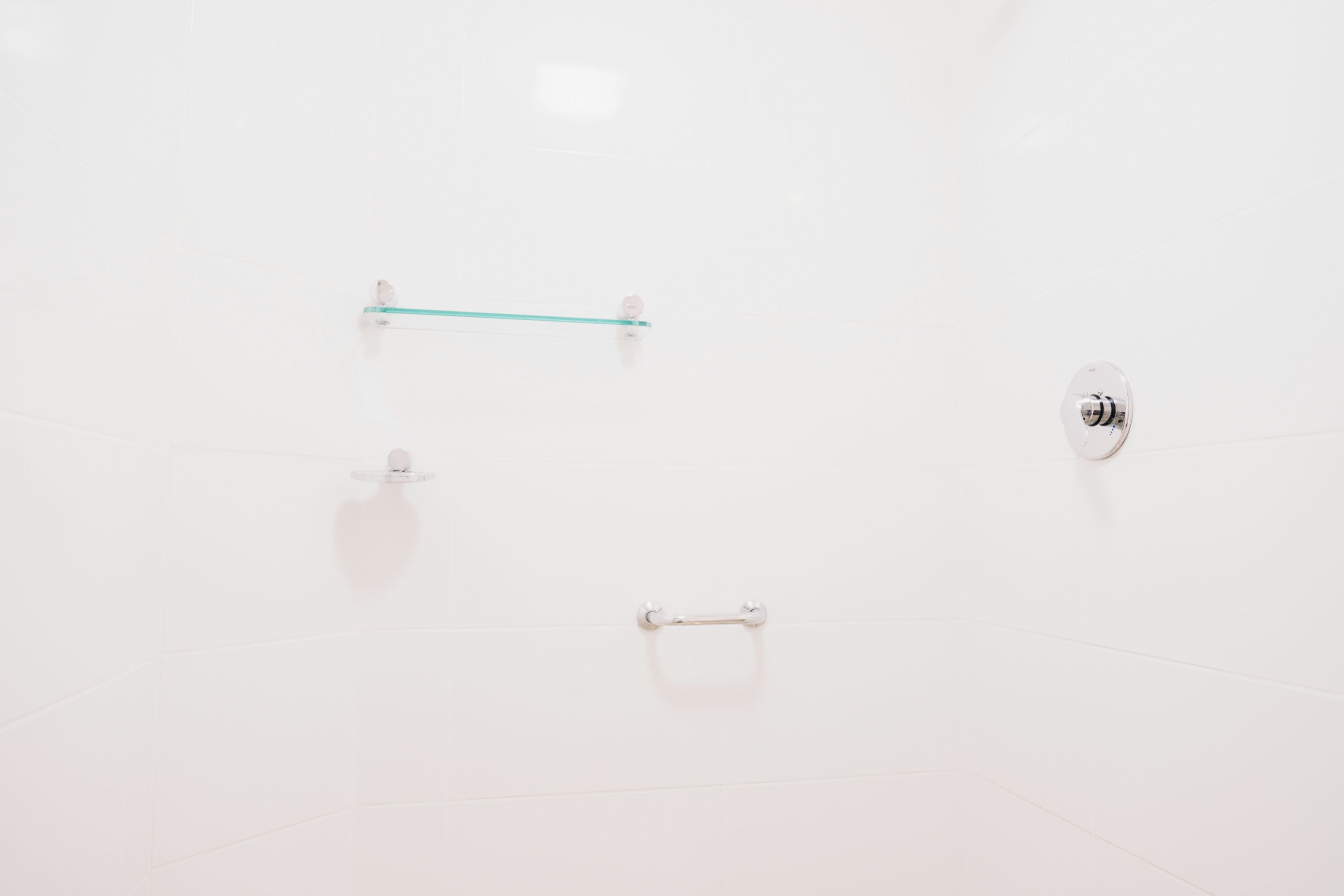 A clean, white interior with a minimalist design, featuring a glass partition and a small, circular object on the floor.
