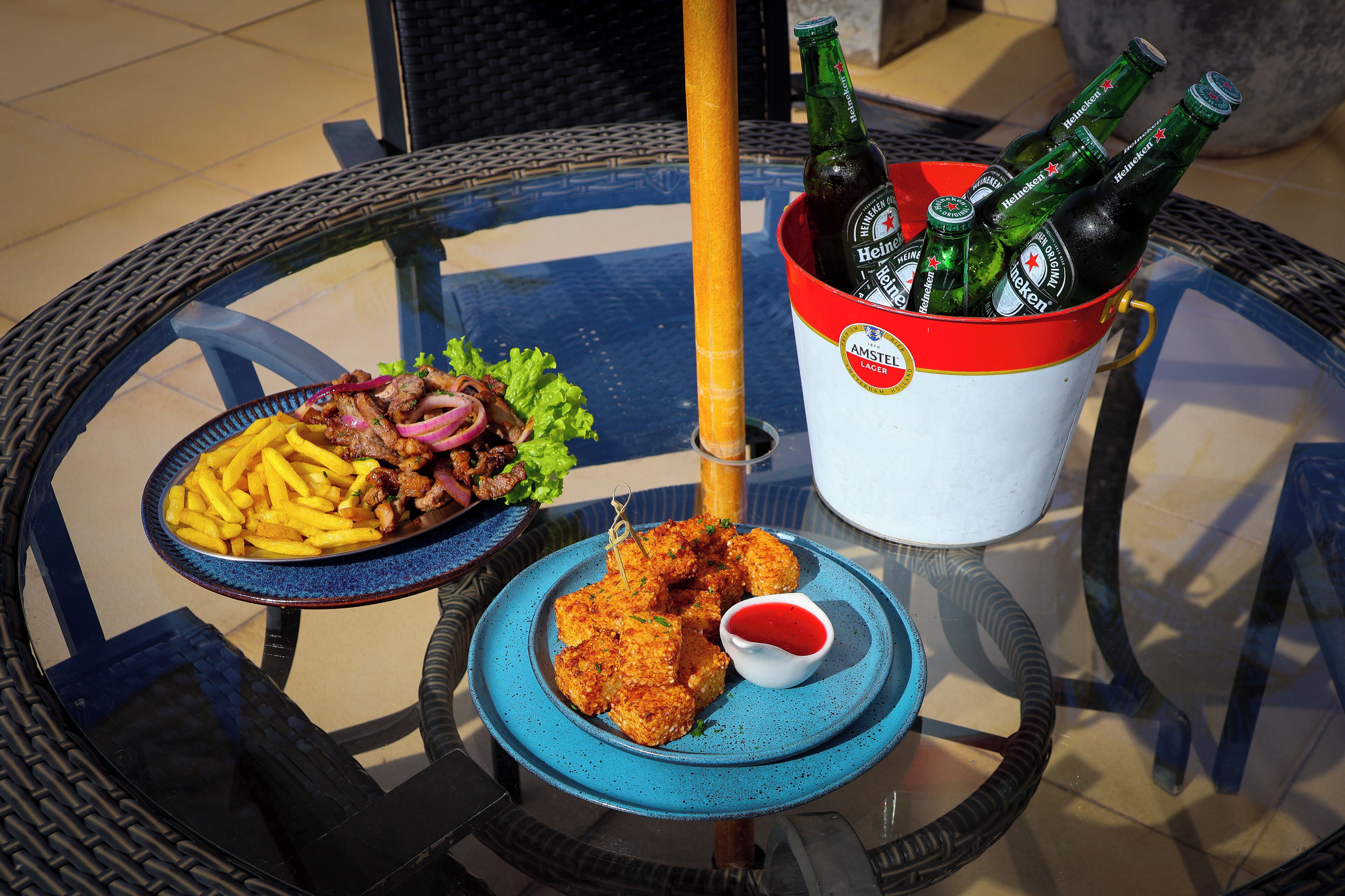 A table with a plate of food, a bucket of beer, and a glass of sauce.
