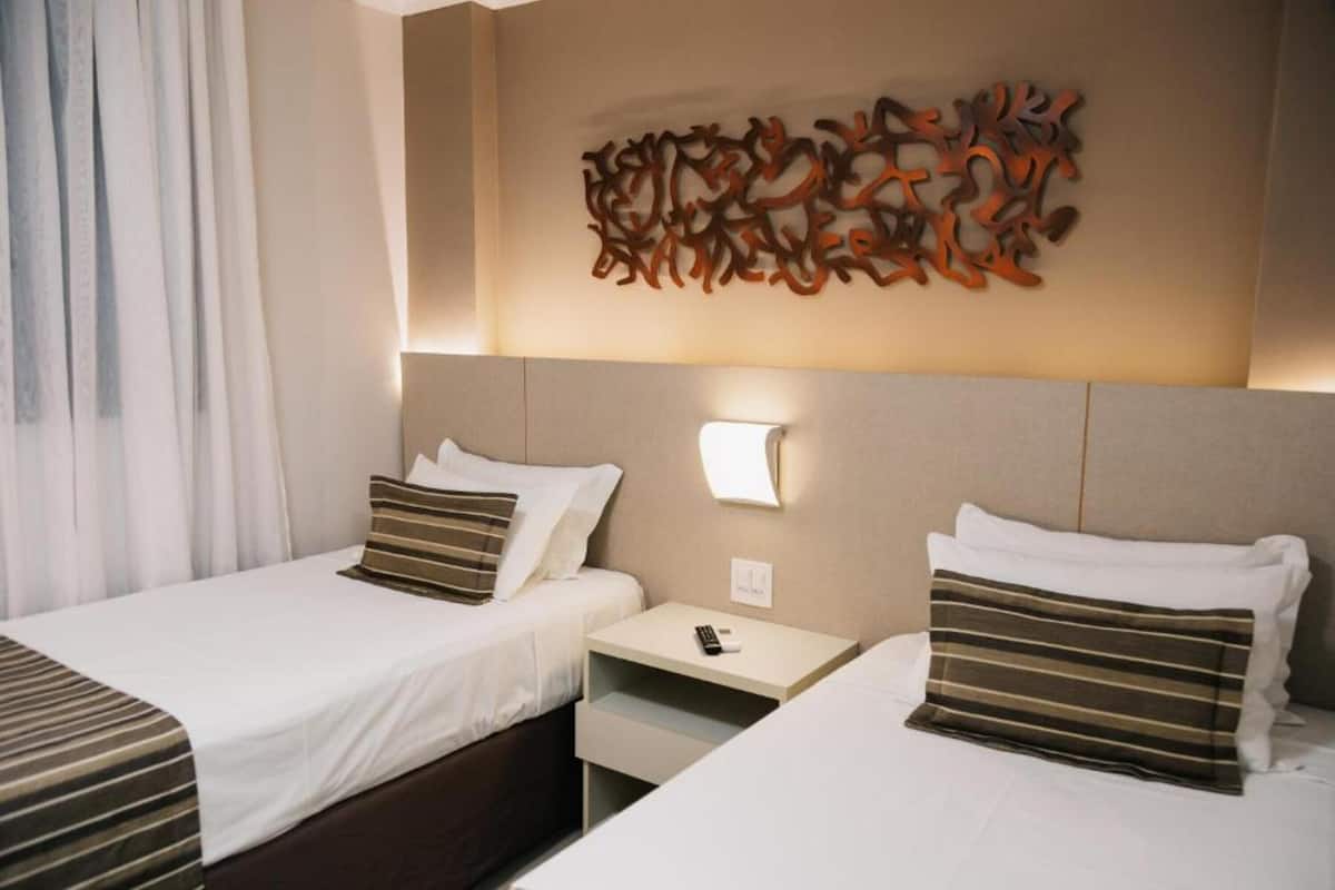 Ein Hotelzimmer mit zwei Betten, einem Nachttisch, einer Wandlampe und einer Wanddekoration.