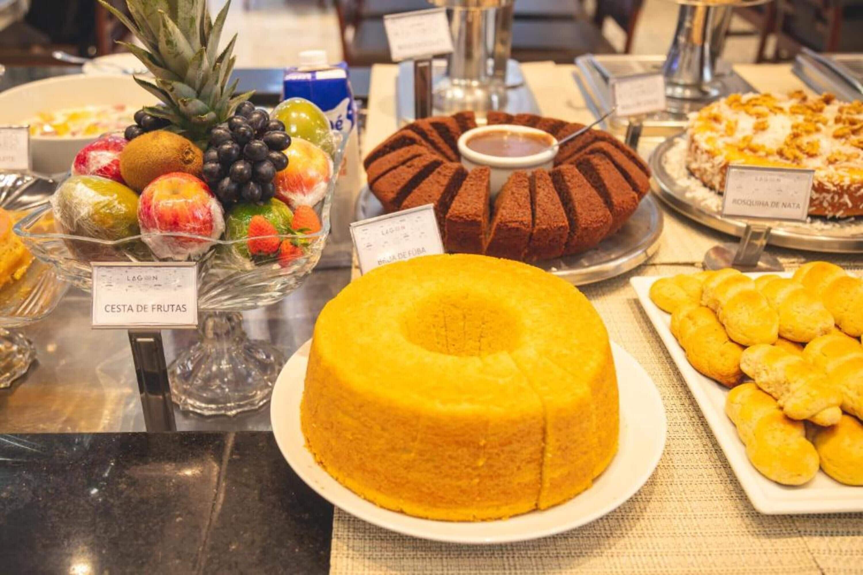 A buffet with various food items including a bundt cake, fruit salad, and pastries.
