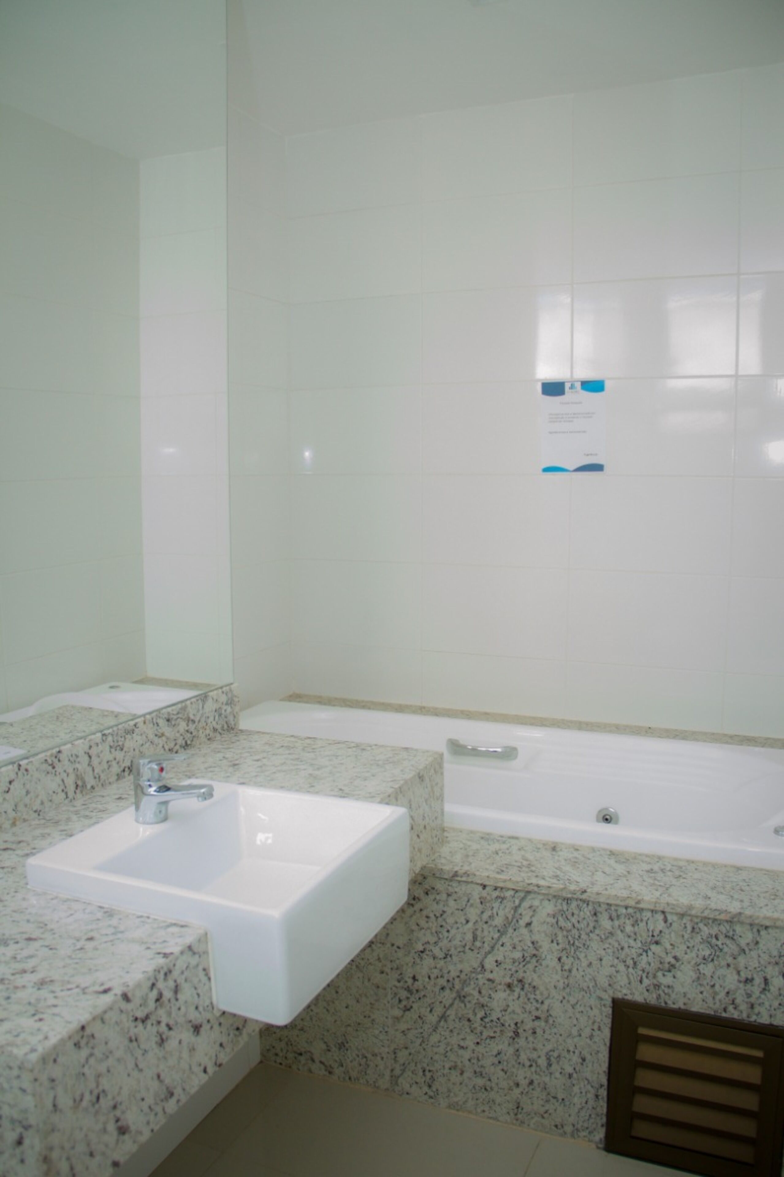 Un baño con un lavamanos blanco, un espejo y una bañera.