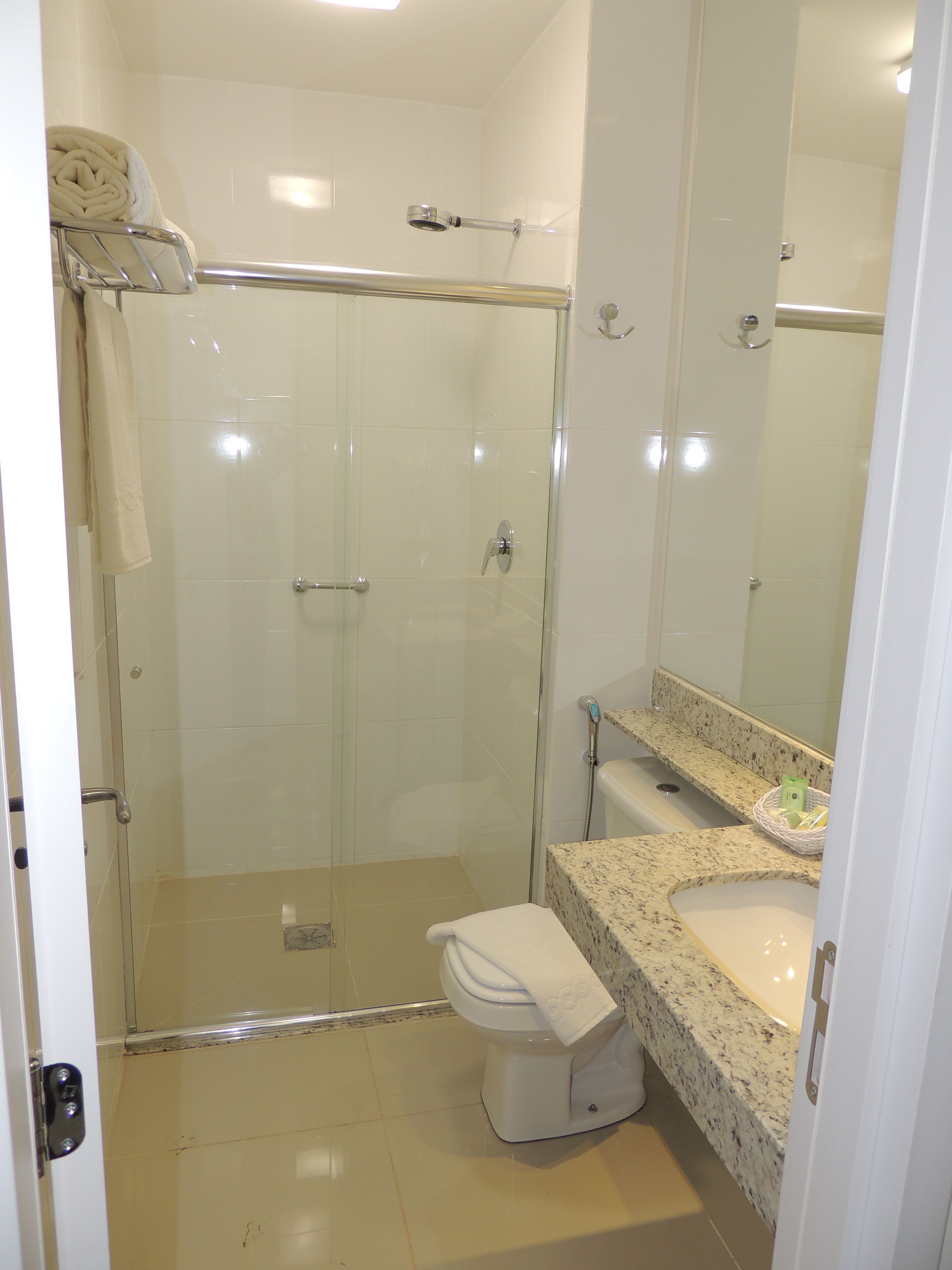 Un baño con ducha de vidrio, inodoro y lavamanos con encimera de mármol.