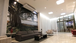 A modern lobby with a large mural, a sofa, a coffee table, and a seating area with chairs. - Lagoon Prime Hotel (Lagoa Santa)