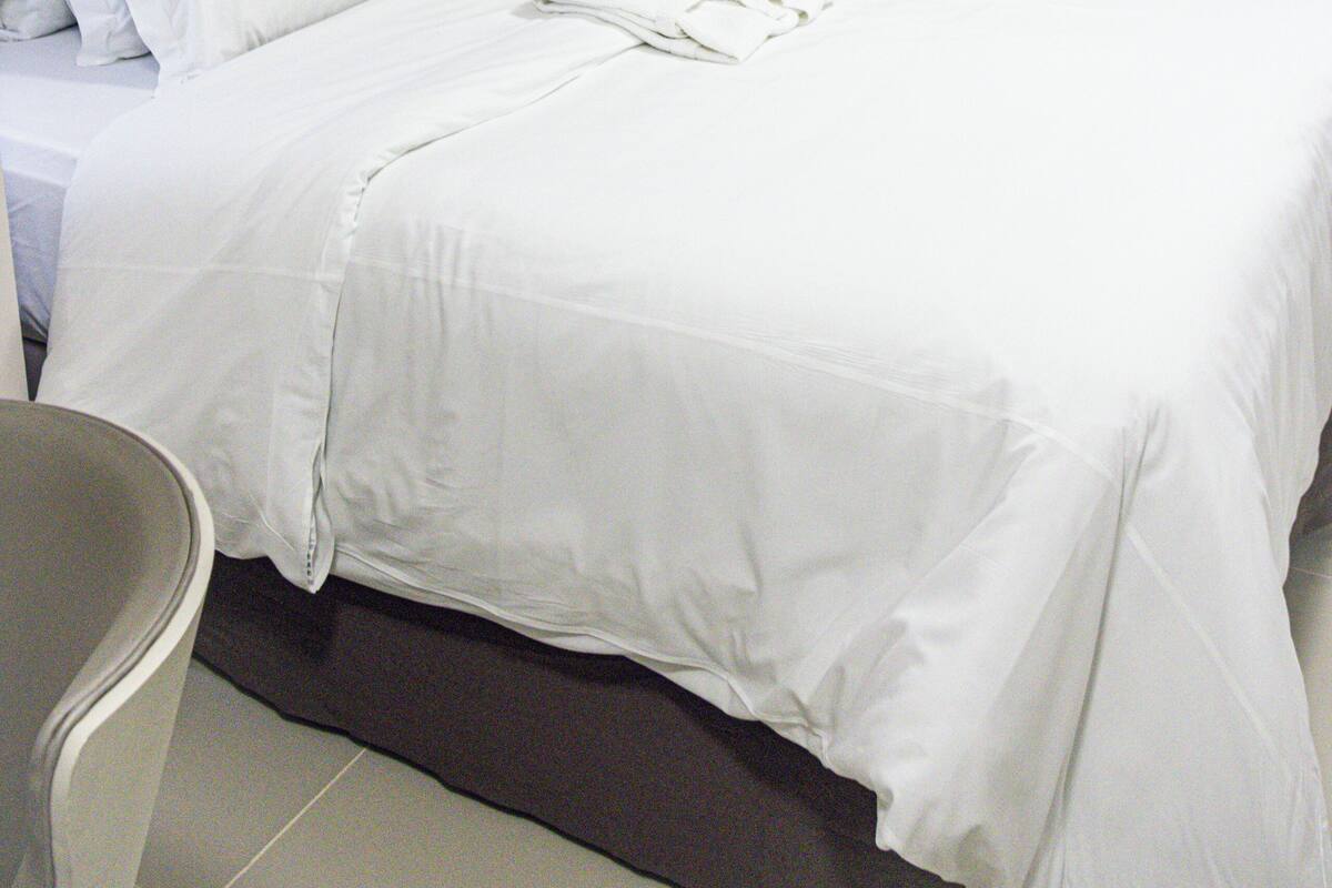 Ein Hotelzimmer mit einem ordentlich bezogenen Bett, einem Nachttisch und einer dekorativen Wandgestaltung.