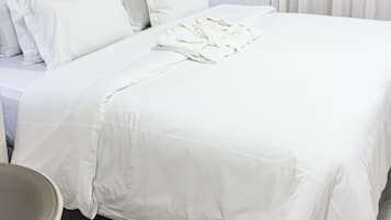 A hotel room with a neatly made bed, a bedside table, and a decorative wall piece.