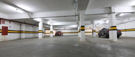 A multi-level parking garage with white pillars and yellow stripes, featuring several parked cars.