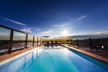 Una piscina al aire libre, sillones reclinables de piscina