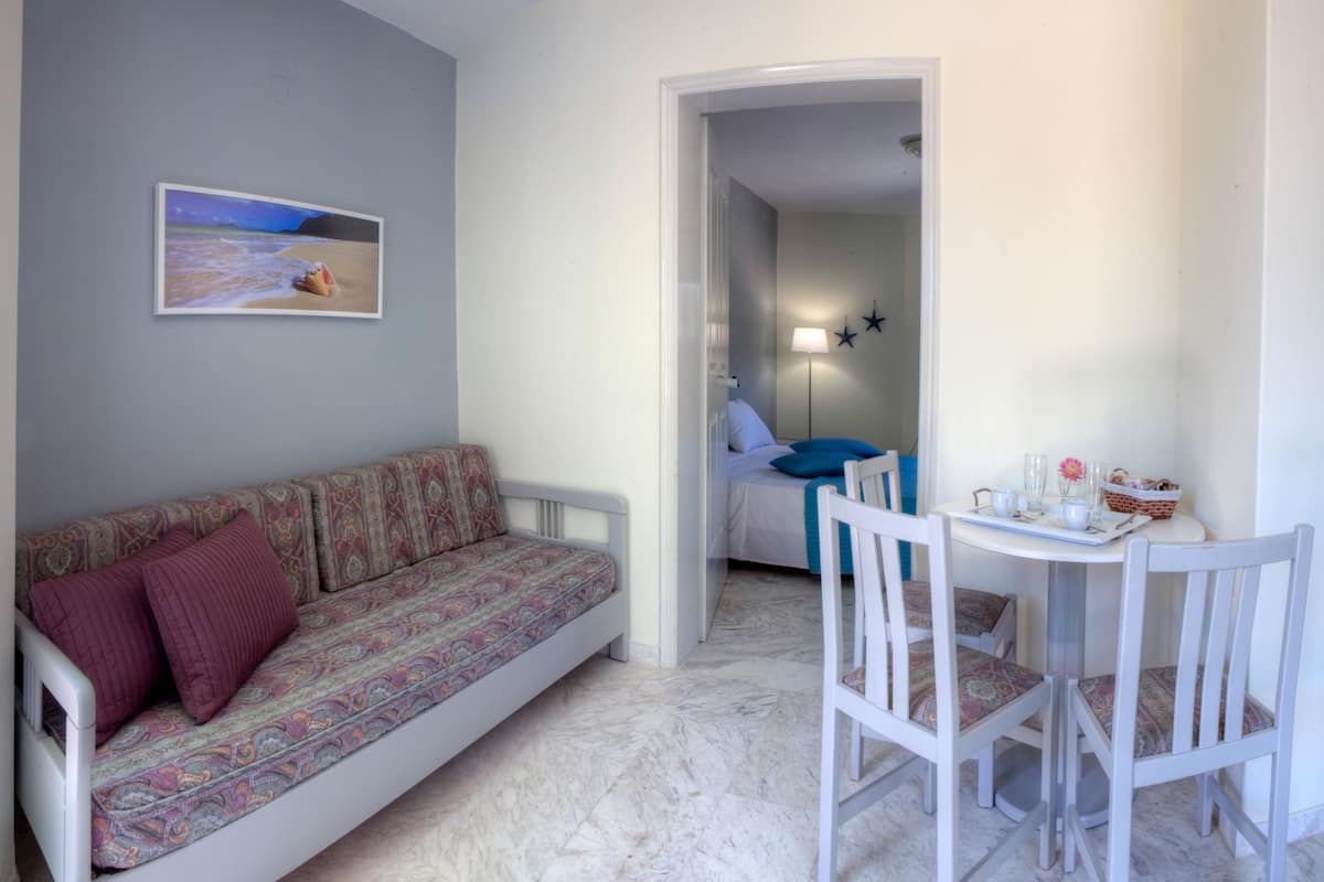 Una habitación con un sofá, una mesa de comedor con sillas, una cama y un cuadro en la pared.