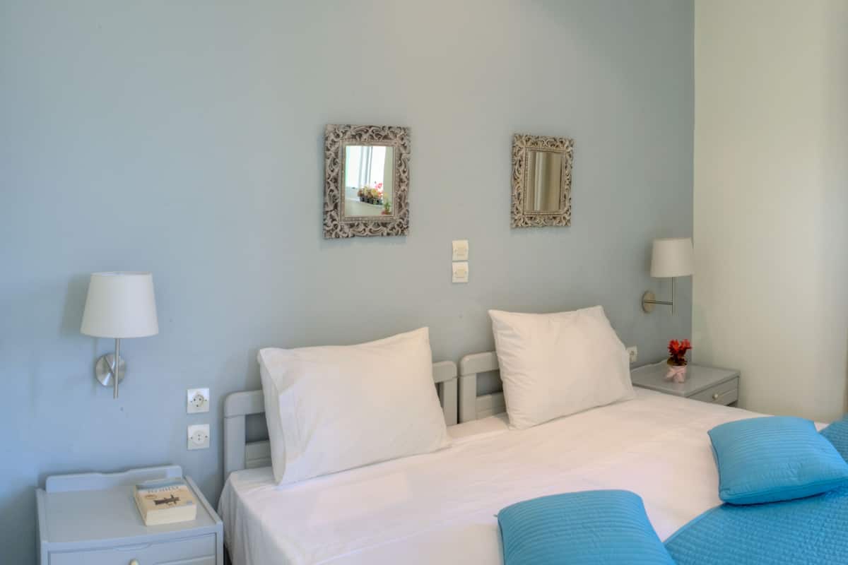 Un dormitorio con una cama grande, dos mesitas de noche y dos lámparas de pared.