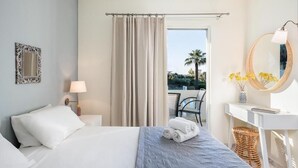 A hotel room with a bed, a desk, a chair, a window with curtains, a balcony, and a view of palm trees. - Villa Life (Chania)