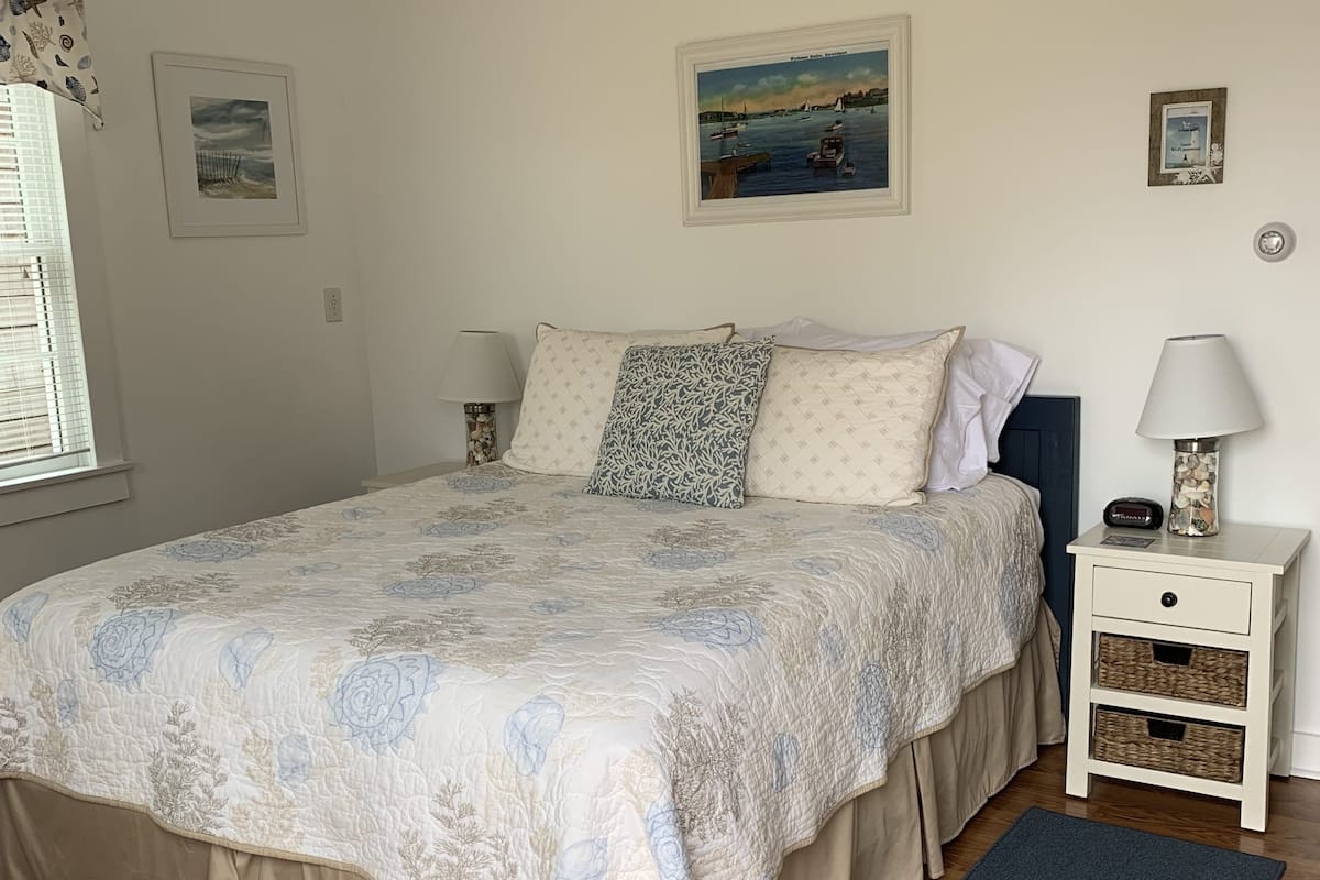 Ein Schlafzimmer mit einem Bett, zwei Nachttischen, einer Wandlampe und einer blauen Fußmatte.