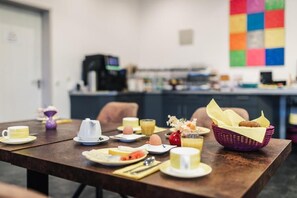 Une table de petit-déjeuner avec des assiettes, des tasses et un panier de pain.