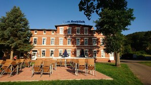 A building with a sign reading "Zum Seeblick" and outdoor seating with wicker chairs and umbrellas. - Hotel Seeblick (Klausdorf)