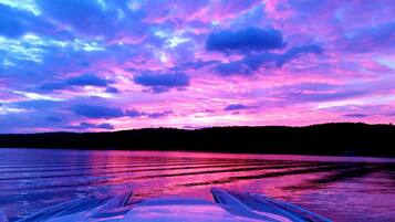 A boat on a lake with a vibrant sunset sky.