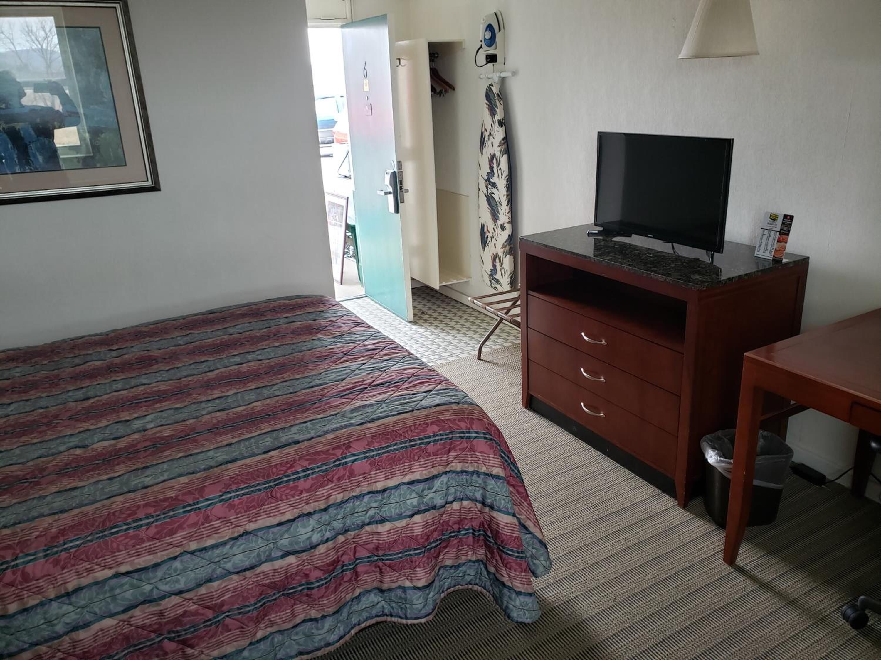 A hotel room with a bed, a desk, a television, and a wardrobe.