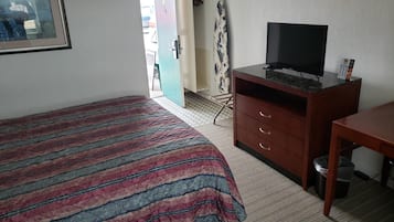 Quarto de hotel com cama, escrivaninha, televisão e guarda-roupa.