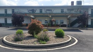 A building with a covered outdoor seating area, a central garden with shrubs, and a staircase leading to an upper level. - Huntingdon Motor Inn (Huntingdon)