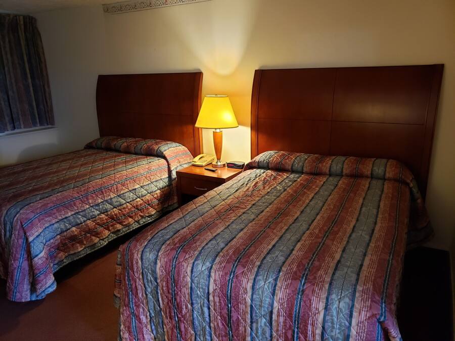 Twee eenpersoonsbedden met houten hoofdborden, een nachtkastje met een lamp en een telefoon.