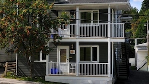 A two-story building with a balcony on the upper floor, a front door, and a small porch area.