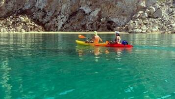 Kayakistas en un lago tranquilo y cristalino, con acantilados rocosos al fondo.