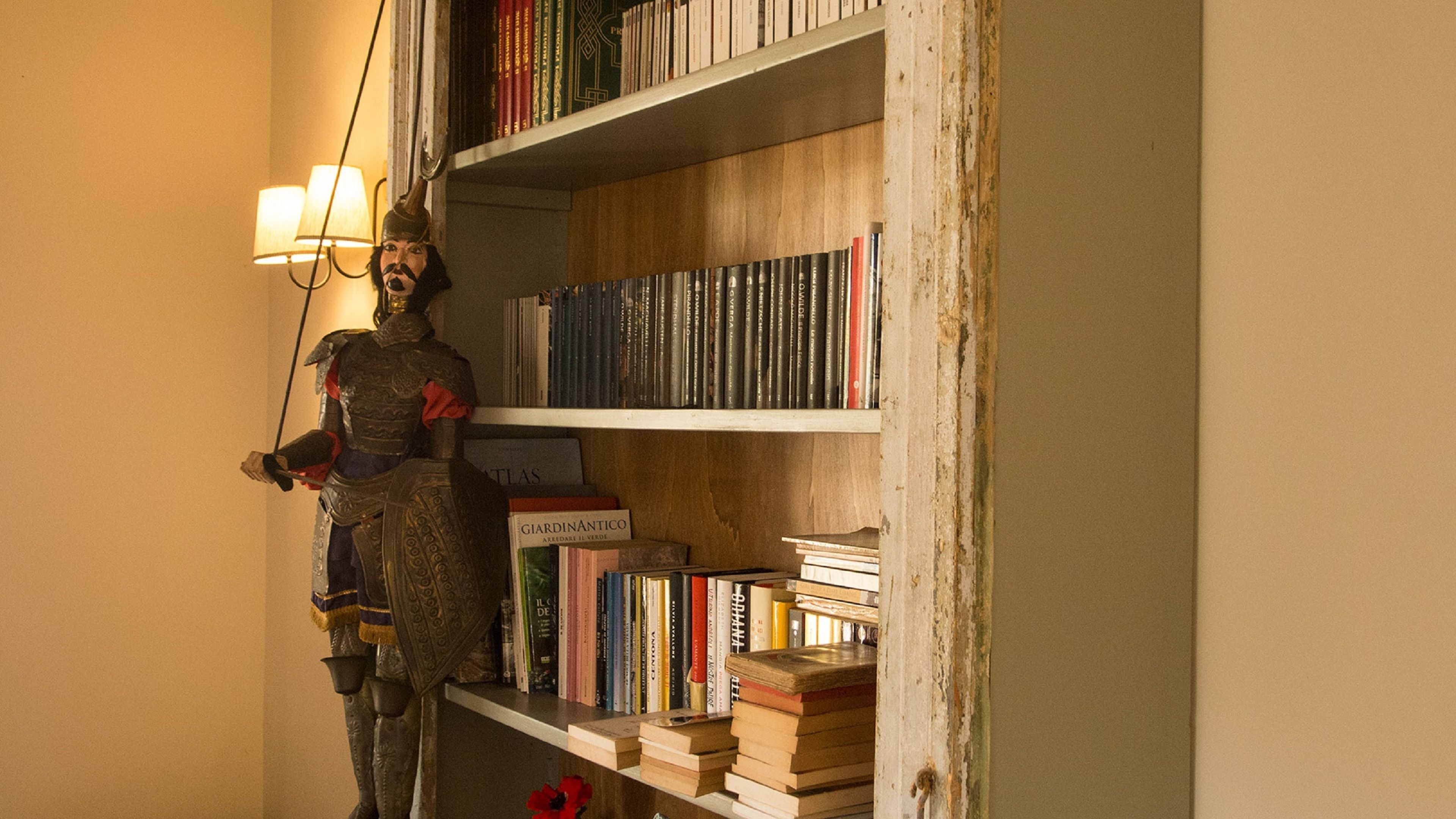 A statue of a knight in armor standing next to a bookshelf filled with books.