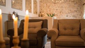 A cozy living room with two sofas, a patterned throw pillow, and a stone wall. - Masseria Agnello Relais (Realmonte)