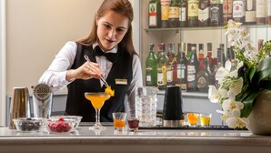 A bartender preparing a cocktail with various ingredients and tools on a bar counter. - Hotel della Conciliazione (Rome)