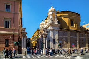 A busy urban street with pedestrians crossing and cyclists riding.