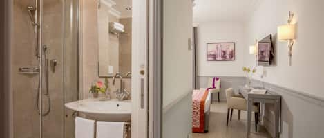Une salle de bain moderne avec une douche à parois de verre, un lavabo avec une serviette et un meuble-lavabo doté d’un miroir et d’appliques murales.