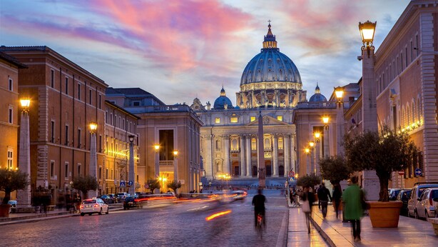 A historic building with a large dome, a cobblestone street, and a person riding a bicycle. - Hotel della Conciliazione (Rome)