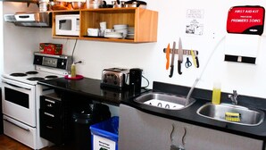 Una cocina compacta equipada con microondas, tostadora, pileta y diversos utensilios.
