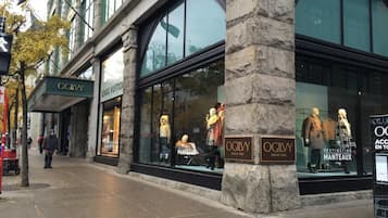 A storefront with large windows displaying mannequins, a sign for 'OGILVY', and a stone pillar.
