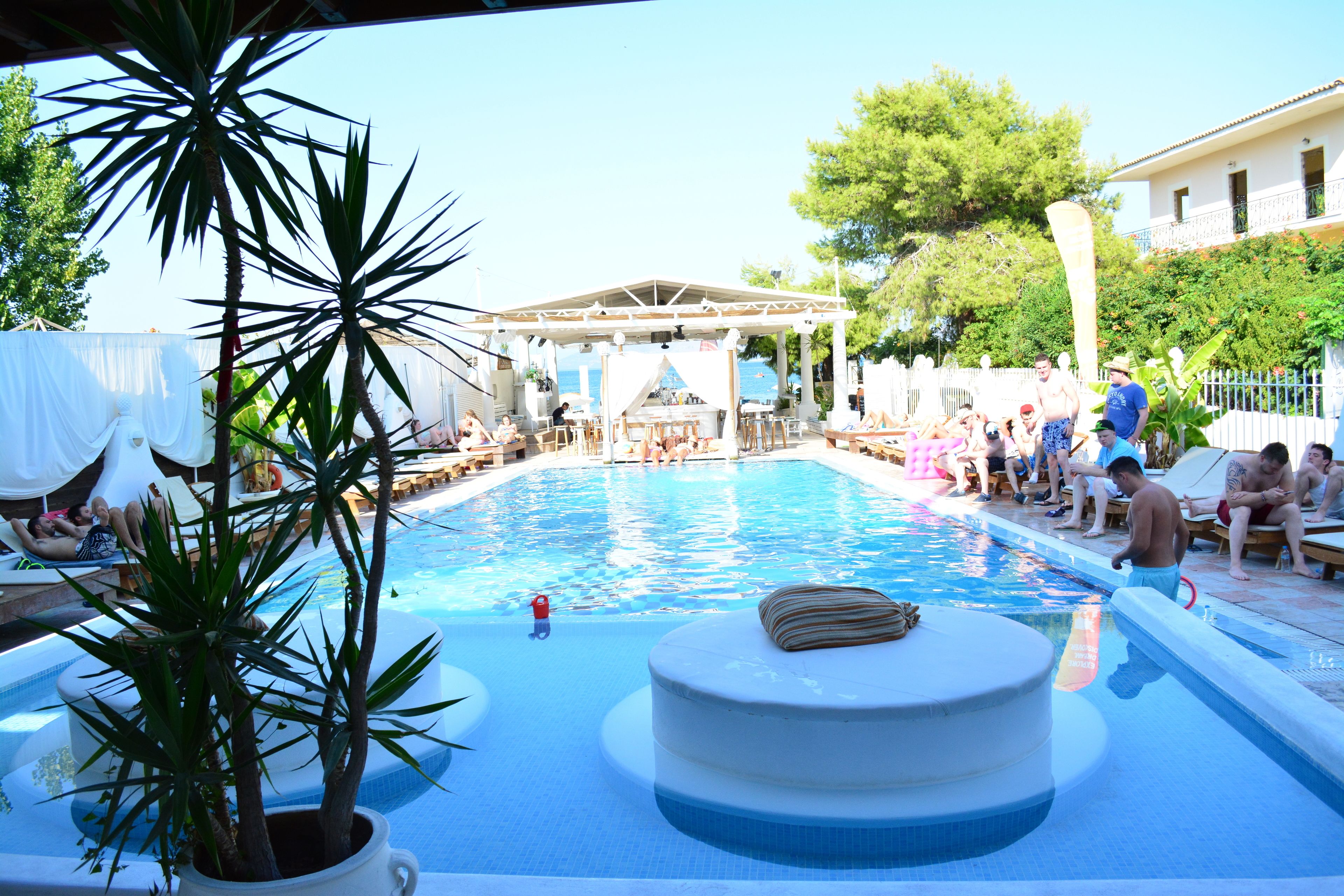 A pool area with lounge chairs and a covered seating area.