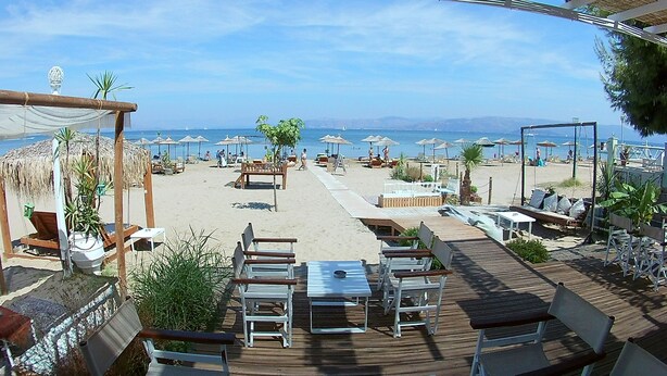 A beachside restaurant with outdoor seating, umbrellas, and a view of the sea. - Cavo D'Oro Apartments (Corfu)