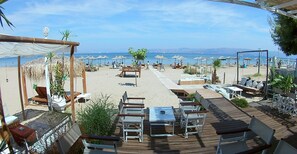 A beachside restaurant with outdoor seating, umbrellas, and a view of the sea. - Cavo D'Oro Apartments (Corfu)