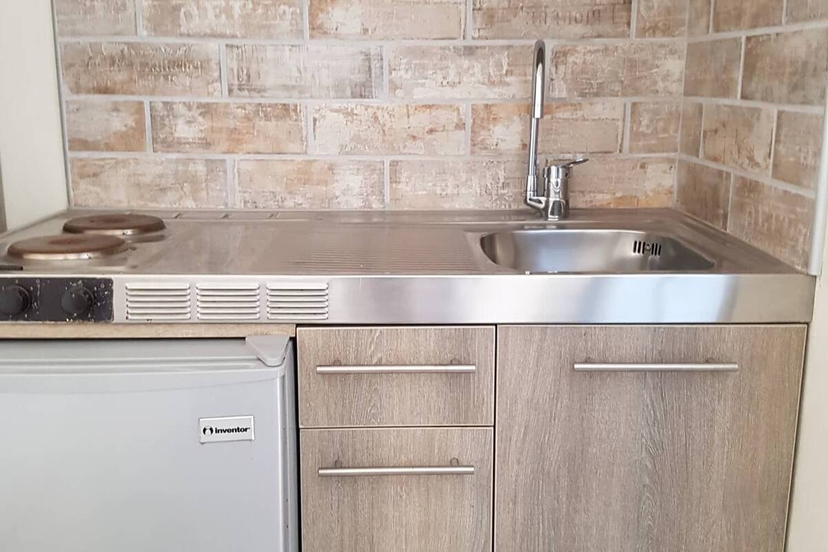 A compact kitchen with a built-in stove, a sink, and wooden cabinets.