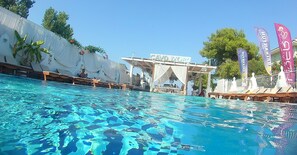 A swimming pool with clear water, surrounded by lounge chairs and a covered area with a sign. - Cavo D'Oro Apartments (Corfu)