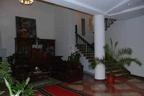 A spacious living area with a fireplace, a staircase, and a large column. - Cajupi (Gjirokastër)