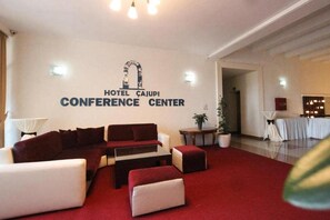 A hotel conference center with a red carpet, sofas, and a table. - Cajupi (Gjirokastër)